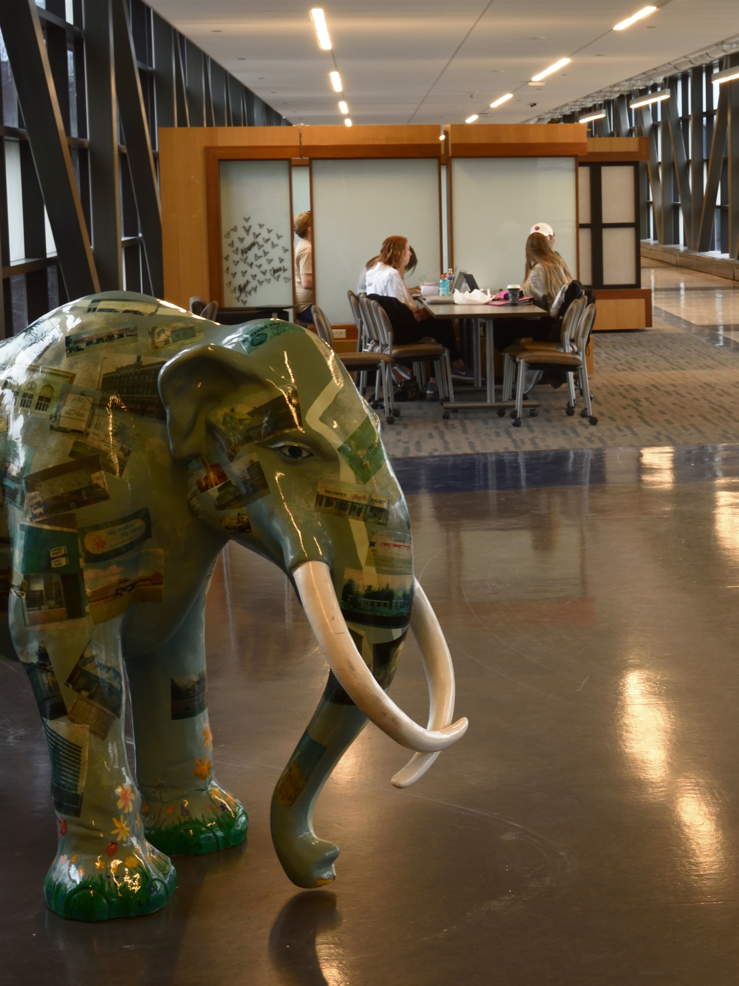 Study group in background with brightly painted mastodon in foreground.
